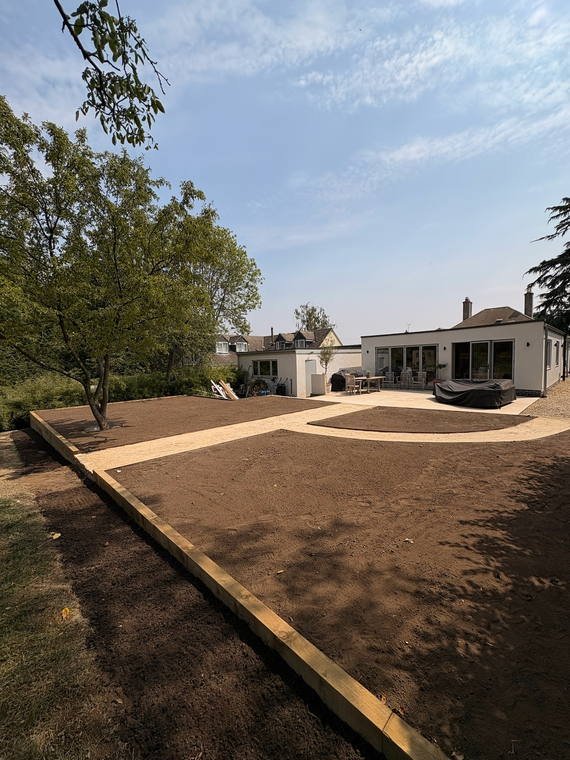 A garden mid-build with sleeper edging and levels set out in fresh soil