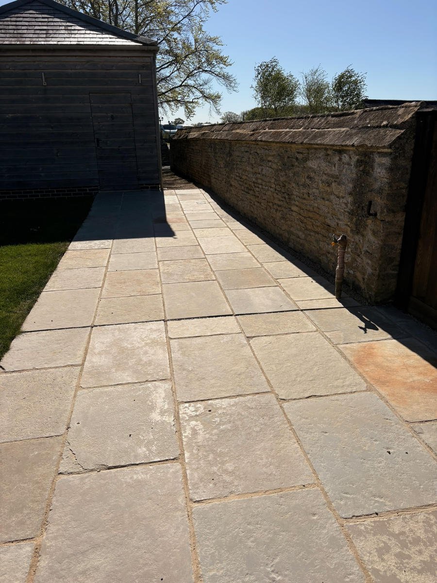 The finished limestone path running between the barn wall and the lawn