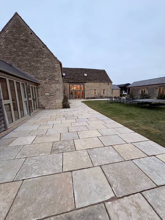 A broad limestone terrace running the length of a converted stone barn at Caswell House