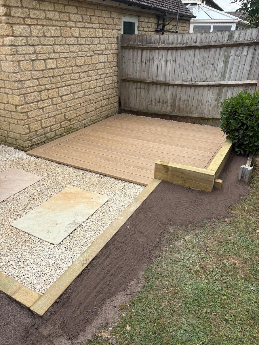 A composite deck meeting sandstone paving and a shingle margin
