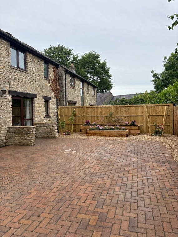 A block-paved courtyard in front of a Cotswold stone house