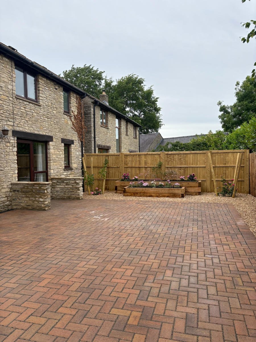 A block-paved courtyard in front of a Cotswold stone house