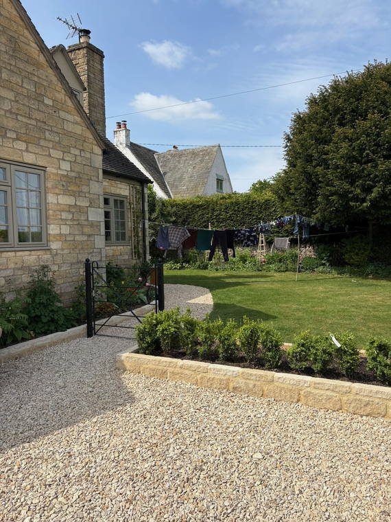 A gravel drive beside a lawn with new box hedging at a Cotswold cottage