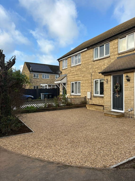 A self-binding gravel drive laid to the front of a stone house with a bay window