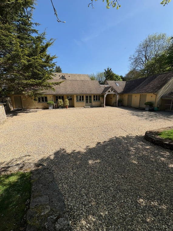 A wide gravel courtyard in front of a long stone house