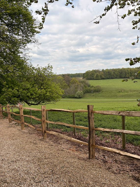 Post-and-rail fencing along a gravel path looking out over open fields