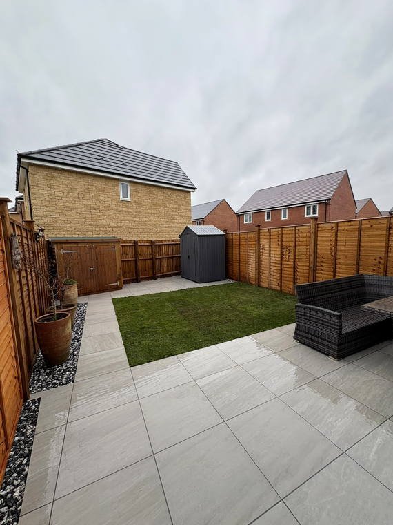 A small garden with porcelain paving, new turf and a shingle margin