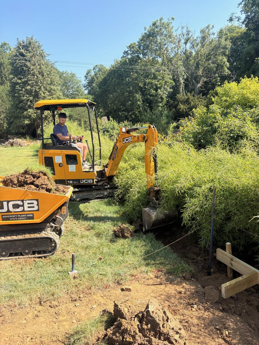 A JCB digger cutting into the bank where the retaining wall will go