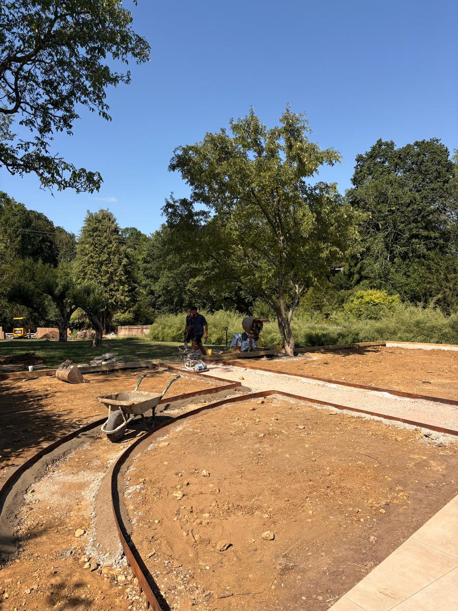The curve of the new path marked out in hose across bare soil