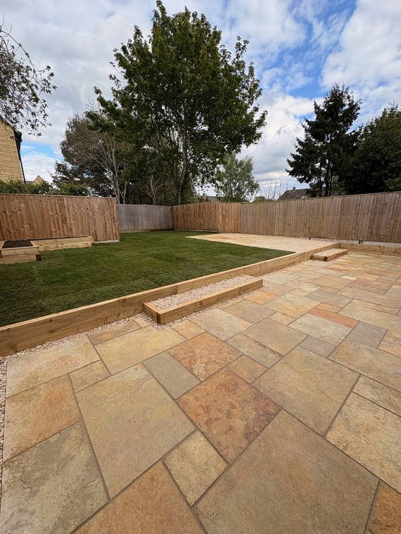 A sandstone patio with sleeper retaining holding back a raised lawn