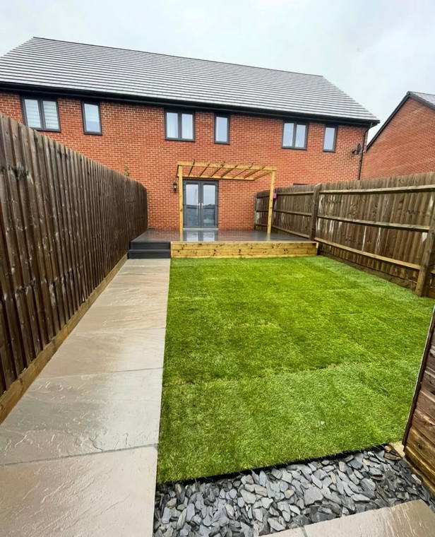 A pergola on a new-build patio with a porcelain path and freshly laid turf