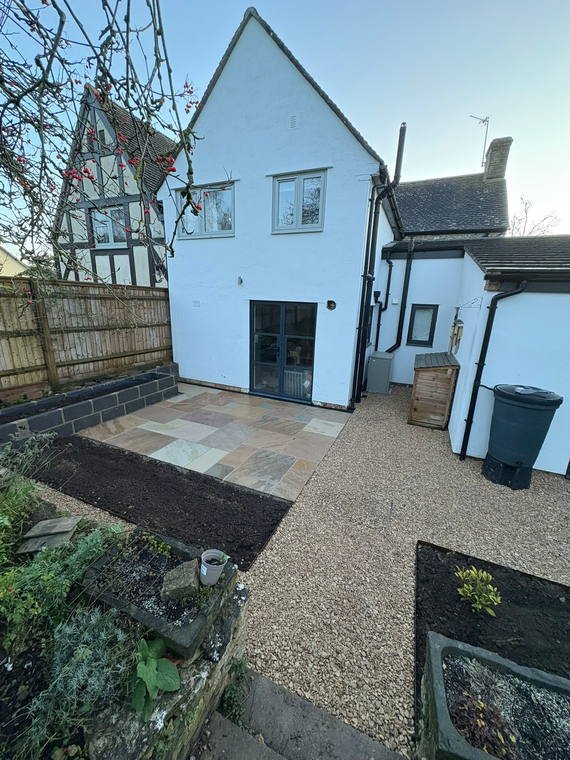 A path of mixed stone and paving running along the side of a rendered house