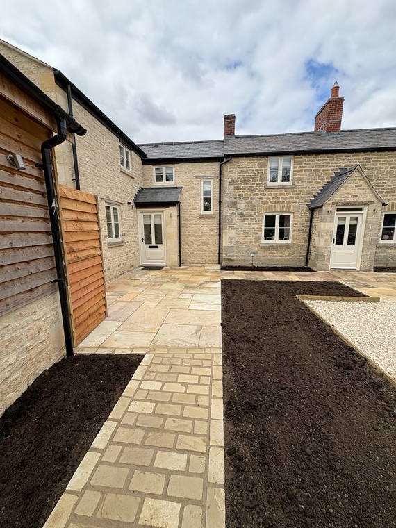 Sandstone paving laid through the courtyard between two stone cottages