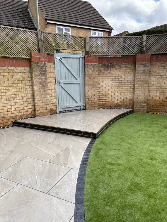 A porcelain patio set between new brick walls, with turf cut to a curve