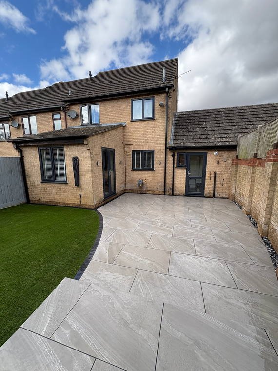 A porcelain path curving round new turf to the back door of a brick house