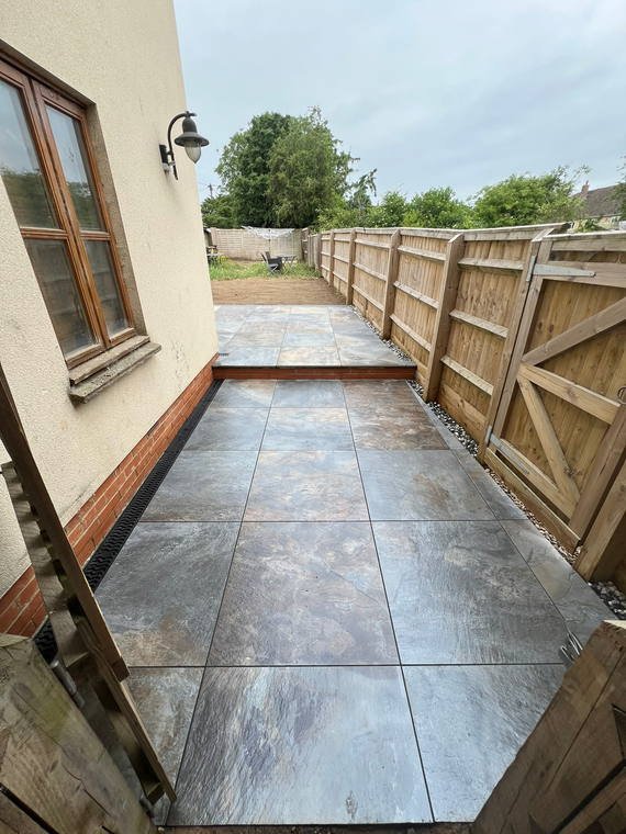 A dark porcelain path running between a rendered wall and a new close-board fence