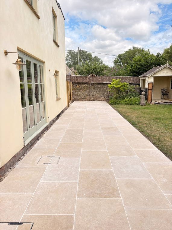 A pale porcelain path running the length of a rendered house towards the lawn