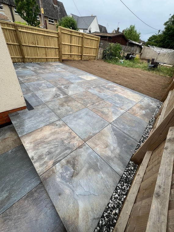 Grey porcelain paving with a shingle margin and a sleeper edge holding the level