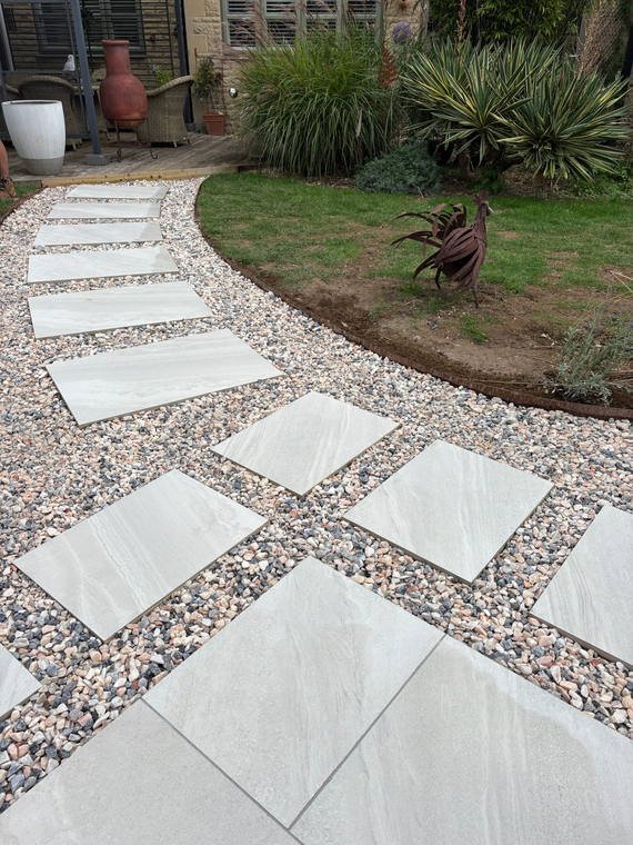 Porcelain stepping stones set through washed gravel, curving across a lawn
