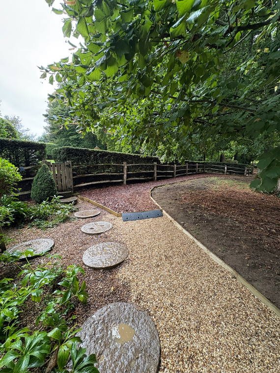 Millstone stepping stones set through bark in a woodland garden