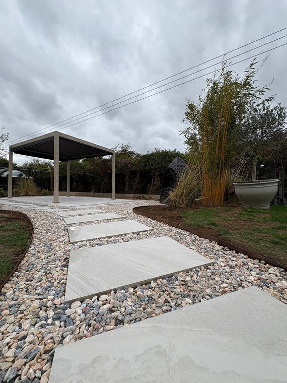Porcelain stepping stones set through shingle leading to a pergola