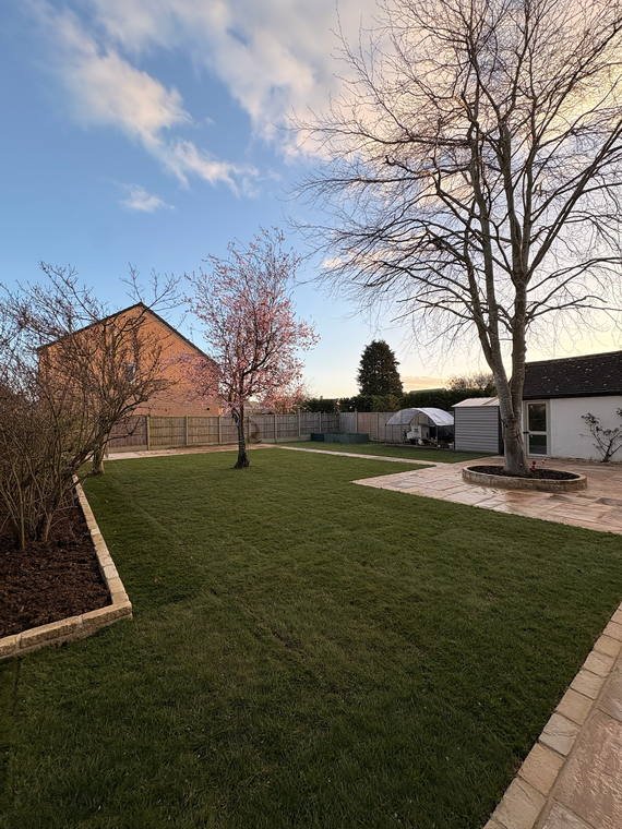 A long lawn edged in sandstone with new beds and a young tree