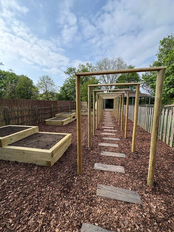 A timber archway walk over stepping stones with raised beds either side