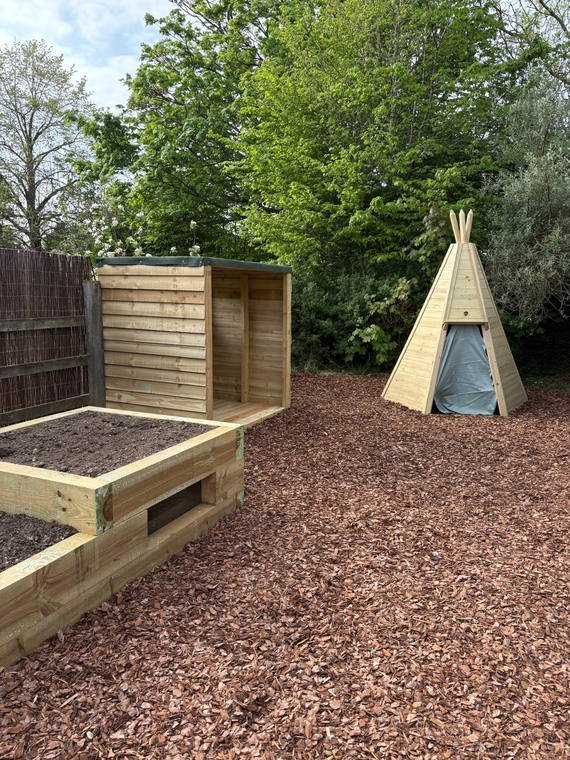 Timber raised beds, bark surfacing and a timber teepee in a school garden