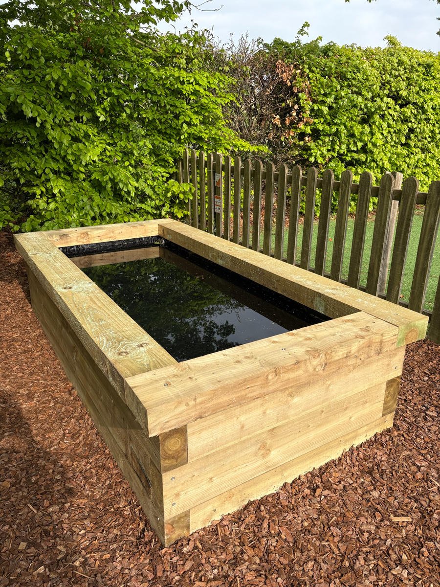 The finished timber-sided pond, filled, with bark surfacing around it