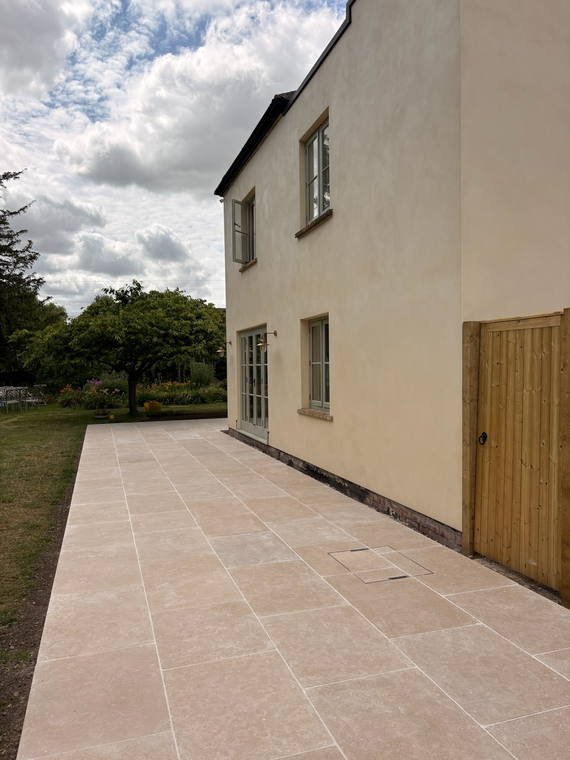 A large pale porcelain terrace running the length of a rendered house