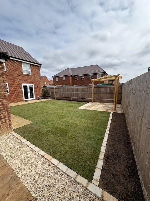 A timber pergola over sandstone paving, with new turf and a gravel margin