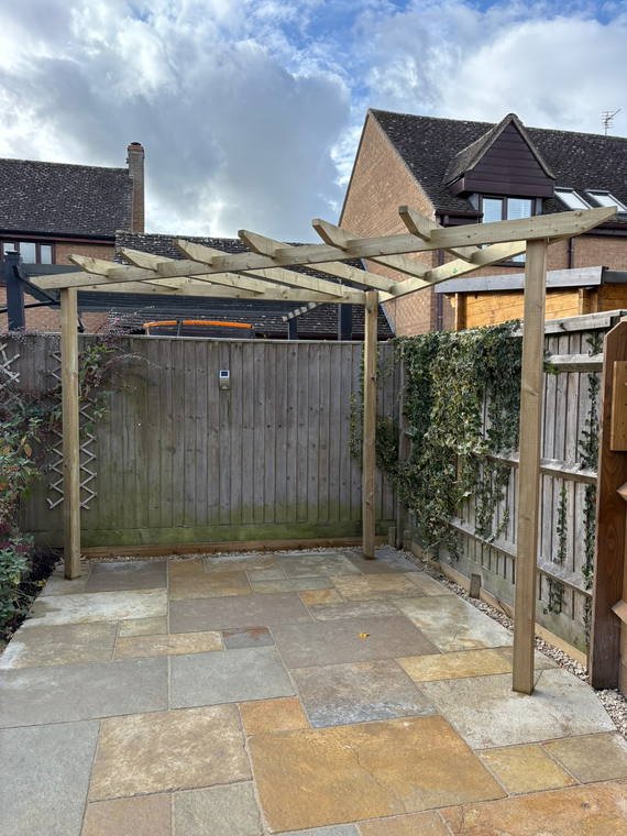 A timber pergola over sandstone paving, with climbers trained up new trellis