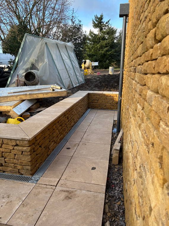 A stone-faced raised bed beside porcelain paving on a new terrace